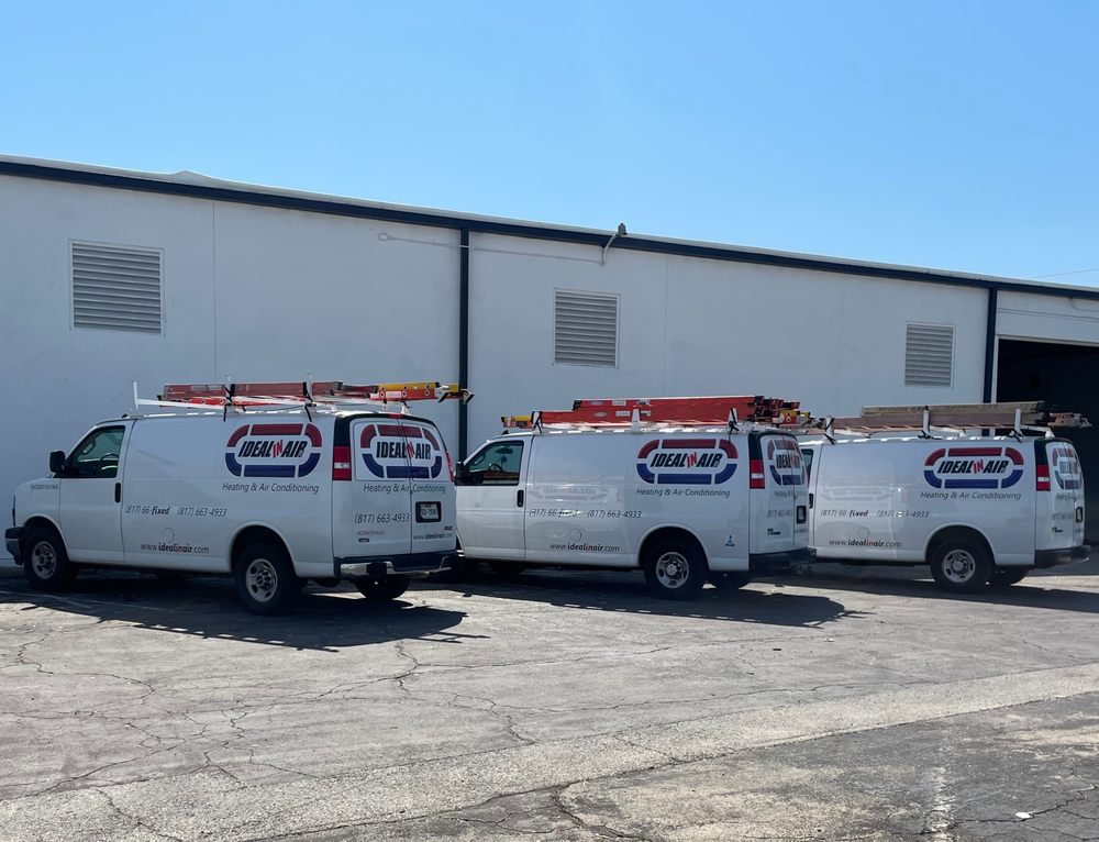 Ideal Air Heating & Air Conditioning service vans parked outside a building. HVAC company vehicles ready for AC repair in Southlake, TX.