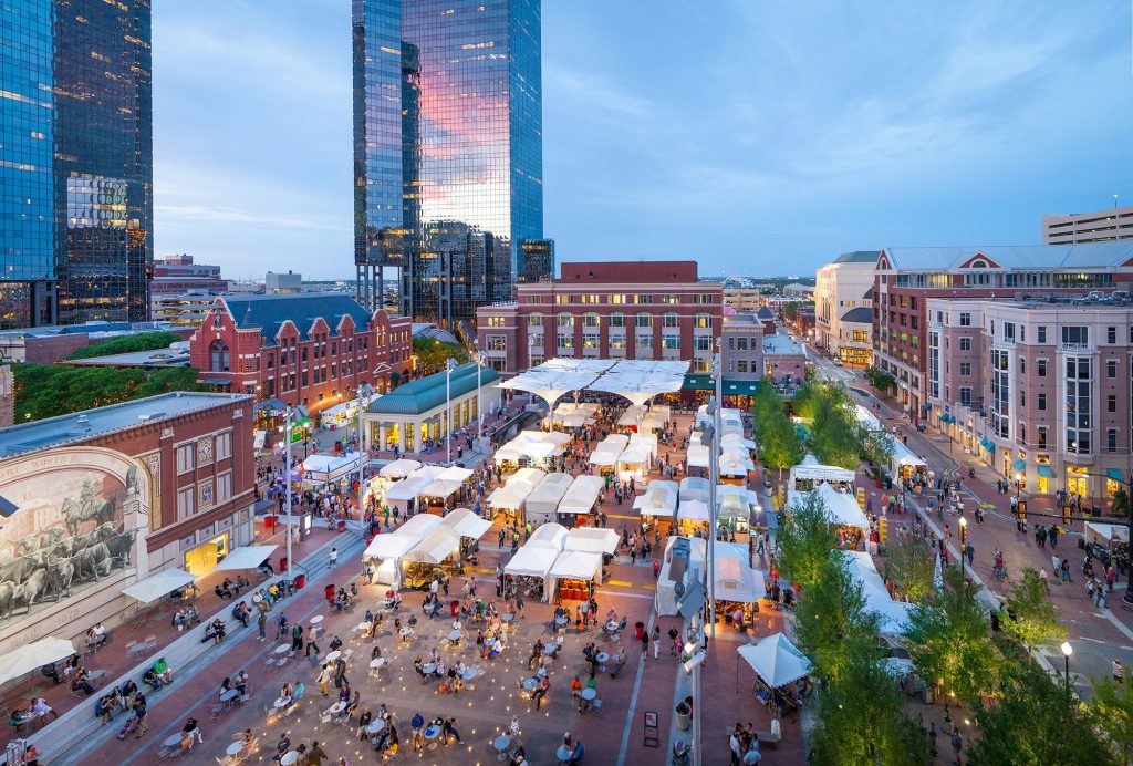 Fort Worth cityscape view of Sundance Square with tents and people at an outdoor event. Tall buildings in the background. Southlake, TX.